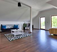 Dachzimmer mit Holzboden, Sofa, Bett und Teppich.
