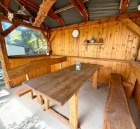 Eine Holzhütte mit einem massiven Tisch und Bänken bietet eine gemütliche Sitzgelegenheit.