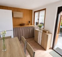 Küche in einer Hütte mit Holzboden, Tisch und weißen Blumen.