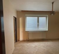 Ein Zimmer mit einem Holzboden in einer 3-Zimmer-Wohnung mit einem Fenster und einem Heizkörper.