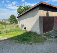 Eine Garage mit geschlossenen Türen in der Haburská-Straße in Prešov neben einem grasbewachsenen Grundstück.