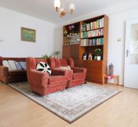Wohnzimmer in einem Einfamilienhaus mit bequemen Sesseln, Teppich und Bücherregal, Boden mit Holzdekor.