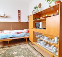 Ein Zimmer in einem Einfamilienhaus mit einem Bett, Retro-Möbeln und Regalen mit Porzellan.