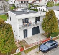 Ein Einfamilienhaus in Martin mit einem Flachdach, neben dem ein Auto parkt.