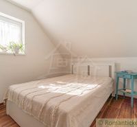 Schlafzimmer in einem Einfamilienhaus mit Bett, Nachttisch und Boden mit Holzdekor.