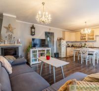 Wohnzimmer in einem Einfamilienhaus mit Kamin, Küche und Holzboden.