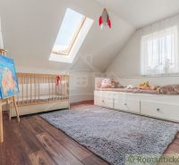 Kinderzimmer mit Bett, Holzelementen und Dachfenster in einem Einfamilienhaus.