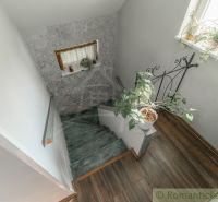 Eine Treppe im Einfamilienhaus mit Blumen und einem Boden in Holzoptik.