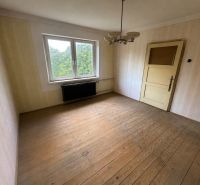Ein Zimmer in einem Einfamilienhaus mit einem Holzboden und einem großen Fenster.