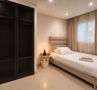 Schlafzimmer in einer 4-Zimmer-Wohnung, einfaches Bett, Nachttisch und Kleiderschrank.