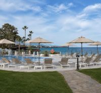 Ein Pool mit Liegestühlen und Palmen am Strand von Dominion Beach in Estepona.