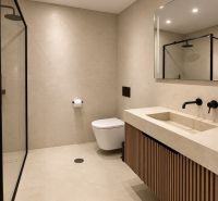 Badezimmer in einer 4-Zimmer-Wohnung mit Duschkabine und Holzdekor auf dem Schrank.