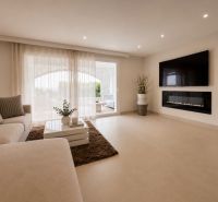 Wohnzimmer einer 4-Zimmer-Wohnung mit einem bequemen Sofa und einem Fernseher an der Wand.