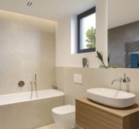 Ein Badezimmer in einem Einfamilienhaus mit freistehender Badewanne und Waschbecken auf einem Holzgestell.