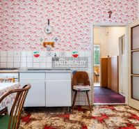 Küche in einem Einfamilienhaus mit Retro-Tapete, weißen Schränken und gemustertem Teppich.