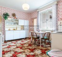 Küche in einem Einfamilienhaus mit retro gemusterten Tapeten, Möbeln und Esstisch.