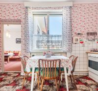 Küche in einem Einfamilienhaus mit Blumenmuster-Tapete, Tisch und Gasherd.
