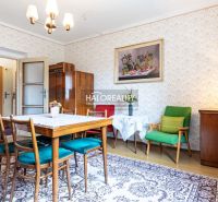 Innenraum eines Einfamilienhauses mit Retro-Möbeln, gemusterten Tapeten und einem Boden mit Holzdekor.