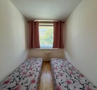 Gemütliches Schlafzimmer in einer 2-Zimmer-Wohnung mit Holzboden und Blumenbettwäsche.