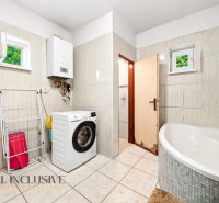 Badezimmer im Einfamilienhaus mit Waschmaschine, Eckbadewanne und Gasheizung.