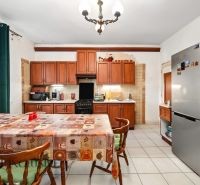 Küche in einem Einfamilienhaus mit Esstisch, Holzschränken und Kühlschrank.
