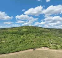 Landwirtschaftliche und forstwirtschaftliche Flächen in Tornaľa mit schönen grünen Hügeln und blauem Himmel.