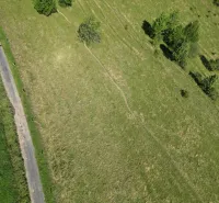 Luftaufnahme der Landschaft bei Stará Ľubovňa, die grüne Wiesen und eine Baumlandschaft hervorhebt.