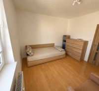Ein Zimmer in einer 3-Zimmer-Wohnung mit einem Bett, einer Kommode und einem Boden in Holzoptik.