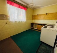 Küche in einer 2-Zimmer-Wohnung mit Linoleumboden und einem Fenster mit Vorhängen.