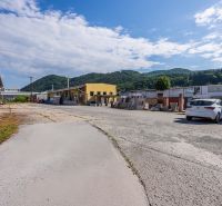 Fassade des Gebäudes an der Zvolenská-Straße, Banská Bystrica, mit Bergkulisse und Himmel.