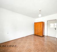 Ein Zimmer in einem Einfamilienhaus mit weißen Wänden, einem Boden in Holzoptik und einem Holzschrank.