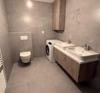 Badezimmer mit Doppelwaschbecken, Waschmaschine und Toilette in einer 3-Zimmer-Wohnung.