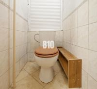 Badezimmer mit Toilette und Holzboden in einer 2-Zimmer-Wohnung.
