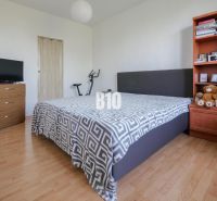 Schlafzimmer in einer 2-Zimmer-Wohnung mit Holzboden, Bett und Regal.
