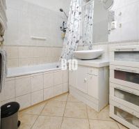 Badezimmer in einer 2-Zimmer-Wohnung mit Badewanne und weißem Waschbecken auf einem Schrank.