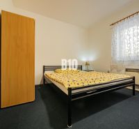 Schlafzimmer in einem Einfamilienhaus mit einem Metallbett, einem Schrank und gemusterten Vorhängen.
