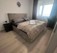 Schlafzimmer in einer 2-Zimmer-Wohnung mit einem Bett und einem Boden in Holzoptik.