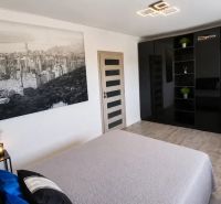 Schlafzimmer mit schwarzem Kleiderschrank, großem Foto und Zimmerpflanzen.