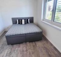 Schlafzimmer mit Bett, Fenster und Holzboden in einem Einfamilienhaus.