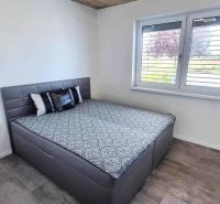 Einfamilienhaus mit einem Bett und einem Boden in Holzoptik, einfache Betondecke.