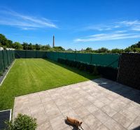 Die Terrasse des Einfamilienhauses in Trnava mit Pflastersteinen und grünem Rasen, der Hund ruht sich aus.