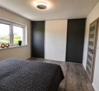 Schlafzimmer in einem Einfamilienhaus mit großem Fenster und Bett, Boden mit Holzdekor.