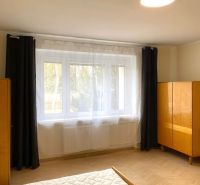 Helles Schlafzimmer mit großem Fenster und Holzboden in einer 3-Zimmer-Wohnung.