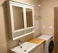 Badezimmer in einer 3-Zimmer-Wohnung mit Waschbecken, Spiegel und Waschmaschine, Keramikfliesen.