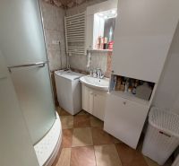 Badezimmer in einer 3-Zimmer-Wohnung mit Waschmaschine, Dusche und Aufbewahrungsschränken.