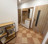 Flur in einer 3-Zimmer-Wohnung mit Fliesen, Garderobenwand und Regalen in Holzoptik.