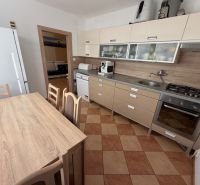 Küche einer 3-Zimmer-Wohnung mit Eckküche, Esstisch und Geräten.