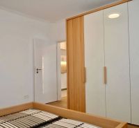 Schrank und Bettrahmen im Zimmer einer 3-Zimmer-Wohnung mit Holzboden.