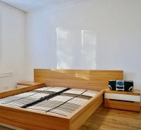 Schlafzimmer mit Bett und Nachttischen in einer 3-Zimmer-Wohnung, Boden mit Holzdekor.