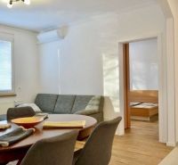Wohnzimmer in einer 3-Zimmer-Wohnung mit Sofa, Esstisch und Boden in Holzoptik.